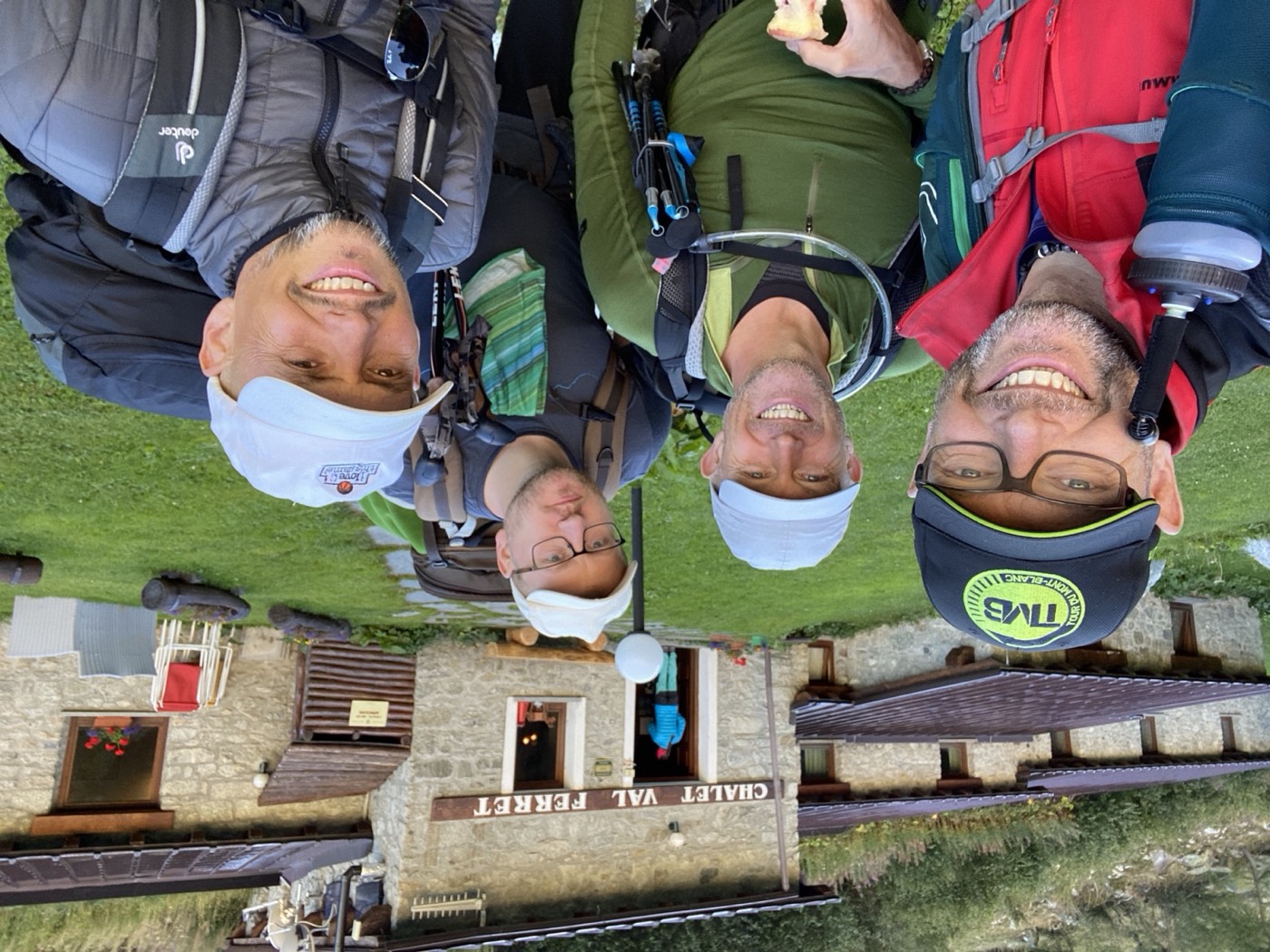 Drei Teilnehmer mit Sonnenhüten vor einer Berghütte